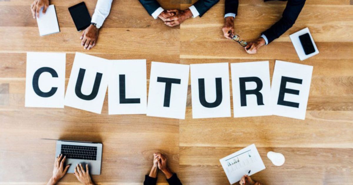 Culture sign displayed on a table with many hands to illustrate "Company Culture."