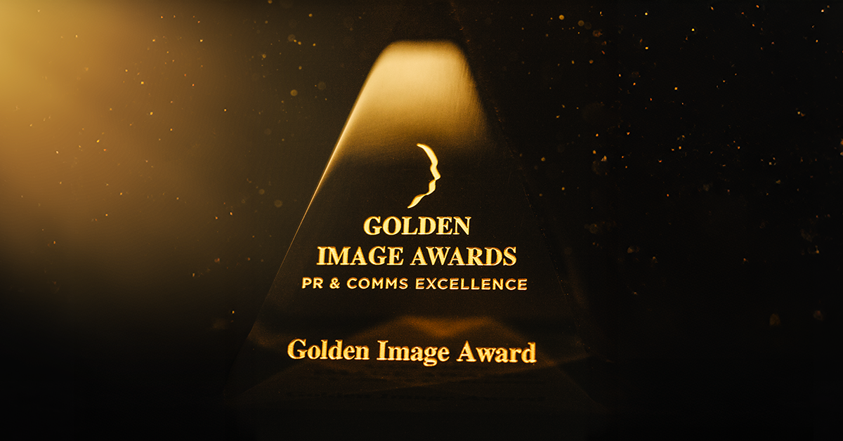 A close-up photograph of the Golden Image Awards pyramid trophy with black background and shining golden spotlight.