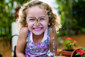 Kid smiling with a butterfly on her nose