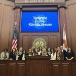 LeadershipFPRA Tallahassee Takeover. FPRA members in a courtroom under a screen with the words, "Welcome to the Florida Senate"
